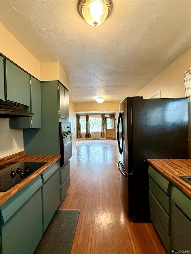 kitchen with butcher block countertops, stainless steel appliances, a textured ceiling, green cabinets, and light hardwood / wood-style floors