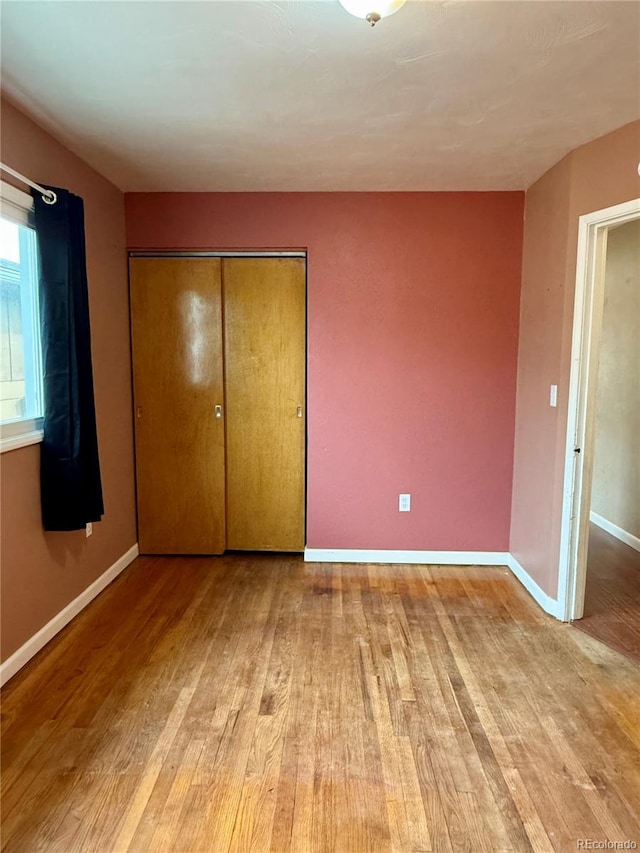 unfurnished bedroom with a closet and light wood-type flooring