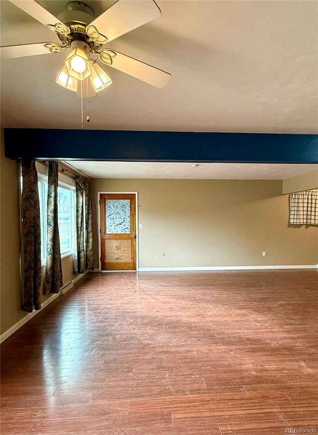 empty room with hardwood / wood-style floors, ceiling fan, and beam ceiling