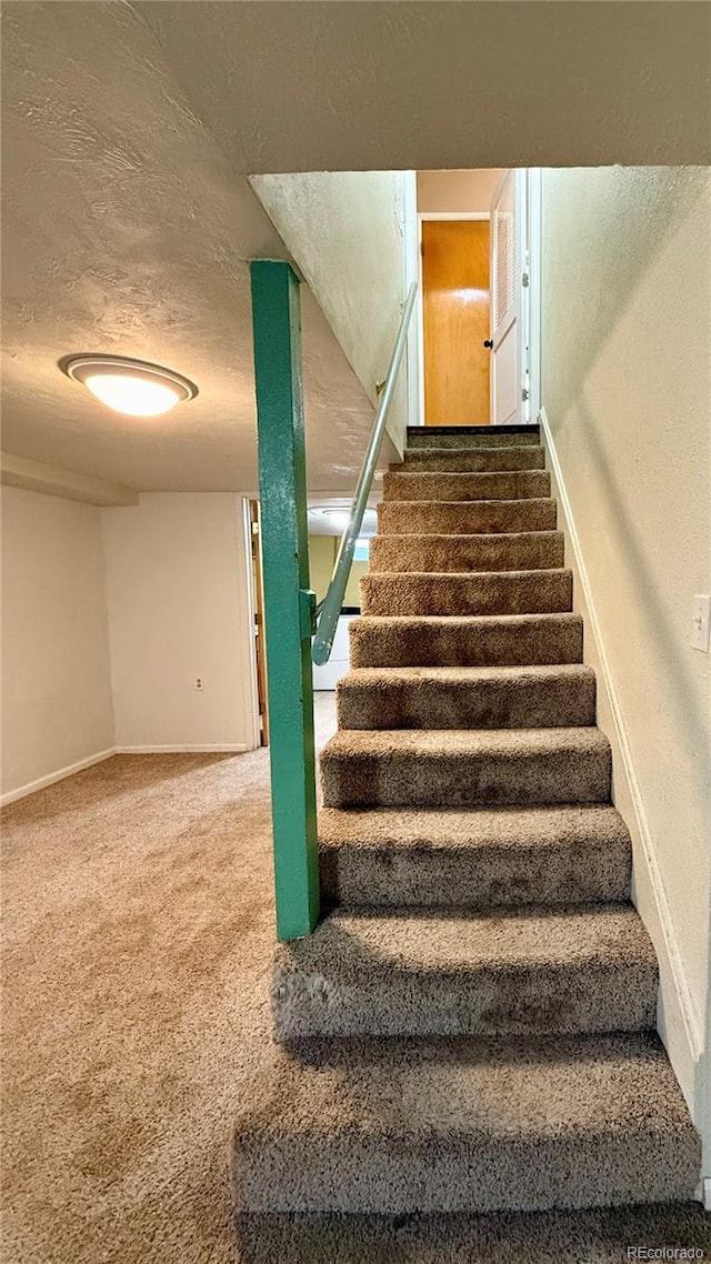 staircase with carpet floors and a textured ceiling