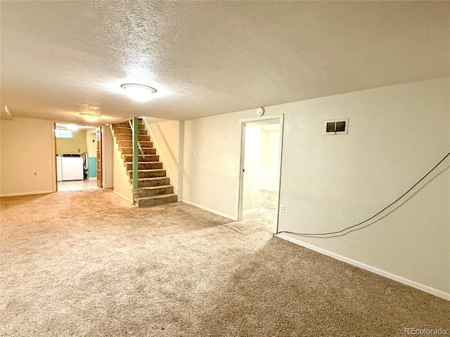 basement with washer / dryer, a textured ceiling, and carpet