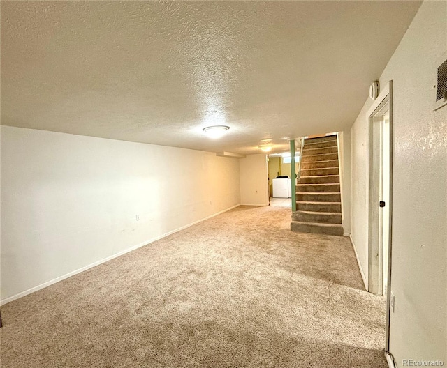 basement with a textured ceiling, light carpet, and washer / clothes dryer