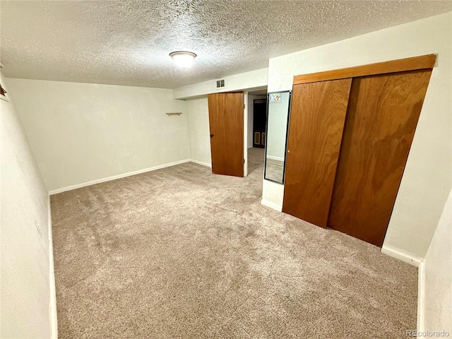 unfurnished bedroom featuring a textured ceiling, light carpet, and a closet