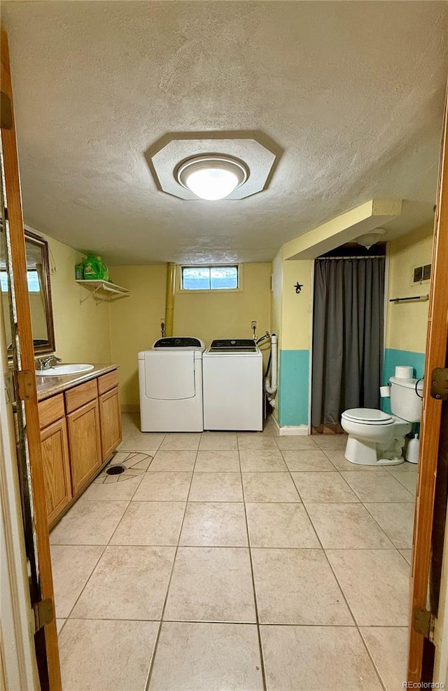 bathroom with tile patterned flooring, a textured ceiling, vanity, washing machine and dryer, and toilet