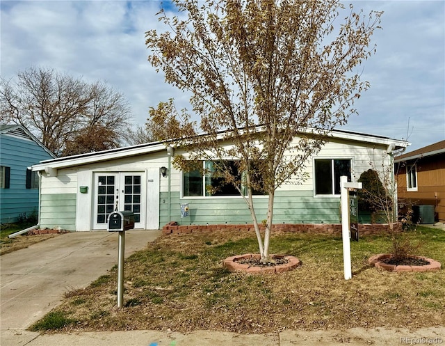 view of front facade featuring central air condition unit, french doors, and a front lawn