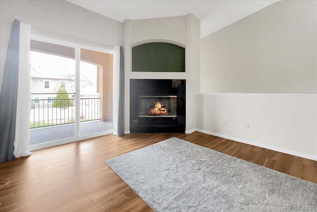 living room featuring wood finished floors, baseboards, and a glass covered fireplace