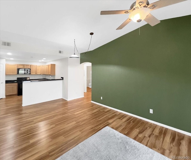unfurnished living room featuring arched walkways, baseboards, visible vents, and wood finished floors
