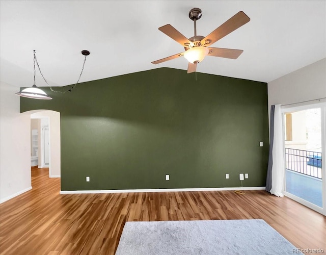 unfurnished room with arched walkways, vaulted ceiling, baseboards, and wood finished floors