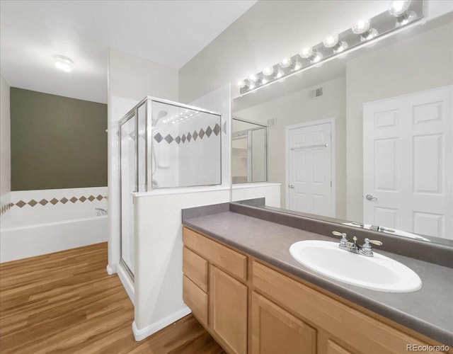 bathroom featuring wood finished floors, vanity, visible vents, a shower stall, and a garden tub