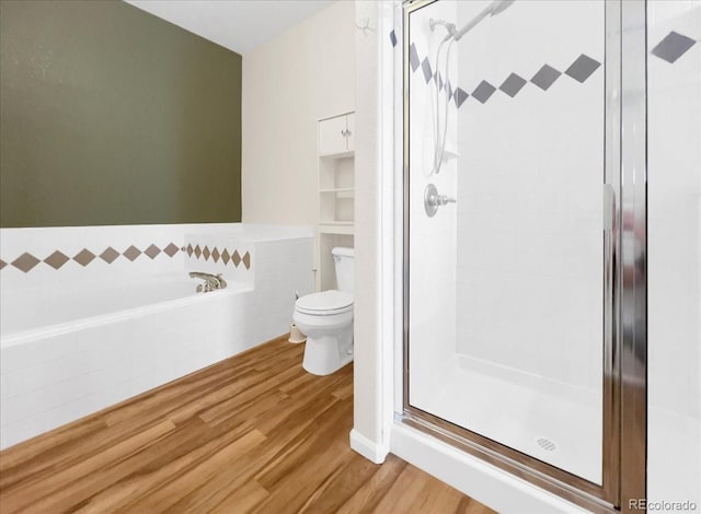 full bath with a bath, toilet, wood finished floors, and a shower stall