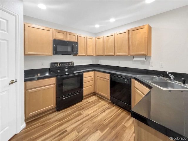 kitchen with light brown cabinets, light wood-style flooring, a sink, black appliances, and dark countertops