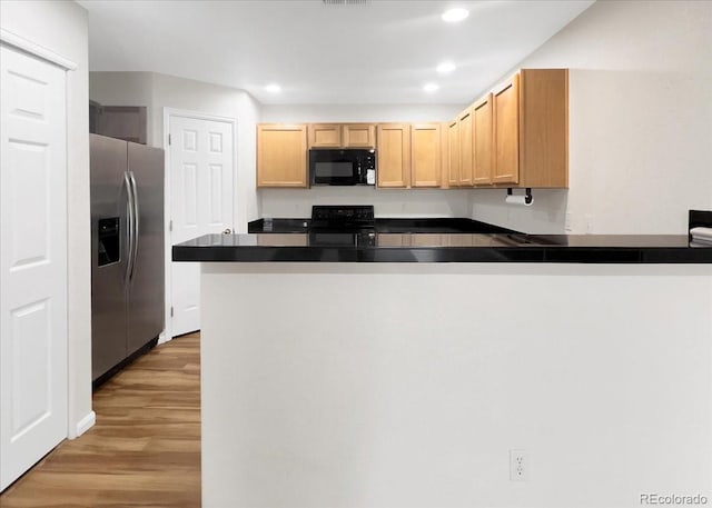 kitchen with a peninsula, light wood-type flooring, black appliances, recessed lighting, and dark countertops