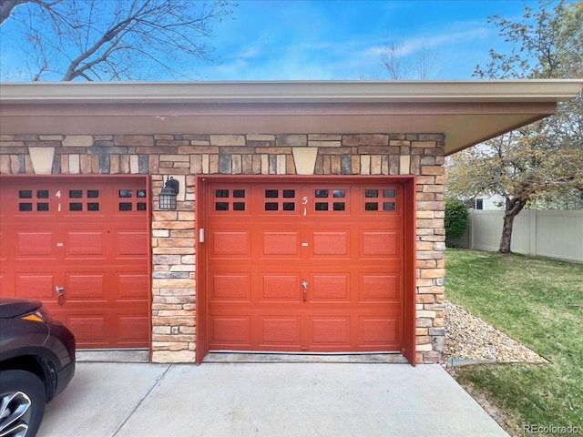garage with concrete driveway and fence