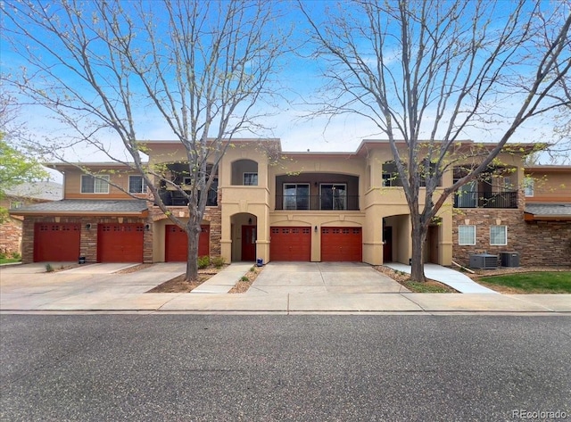 view of front facade with central AC unit, an attached garage, stucco siding, and driveway