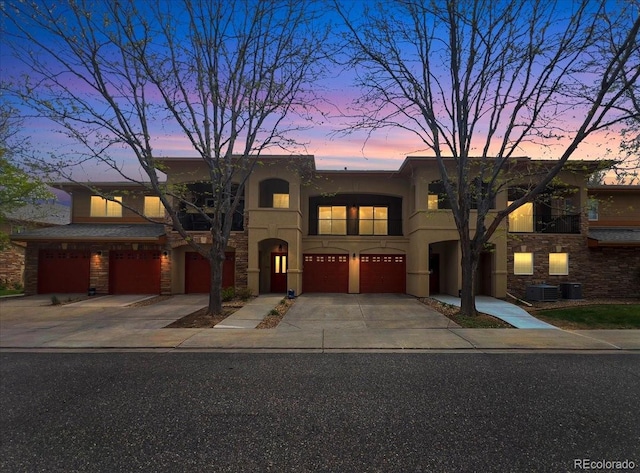 view of front of house featuring central air condition unit, a garage, stucco siding, and driveway