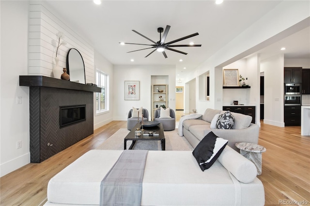 living room featuring a fireplace, light wood-type flooring, and ceiling fan