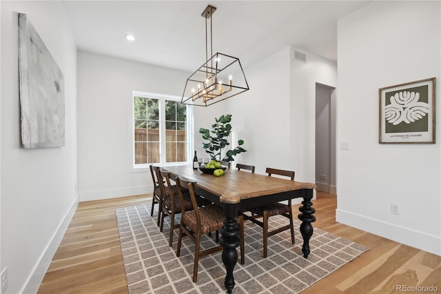 dining space featuring light wood-type flooring and a chandelier