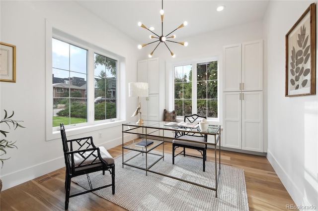 office with light wood-type flooring and a notable chandelier