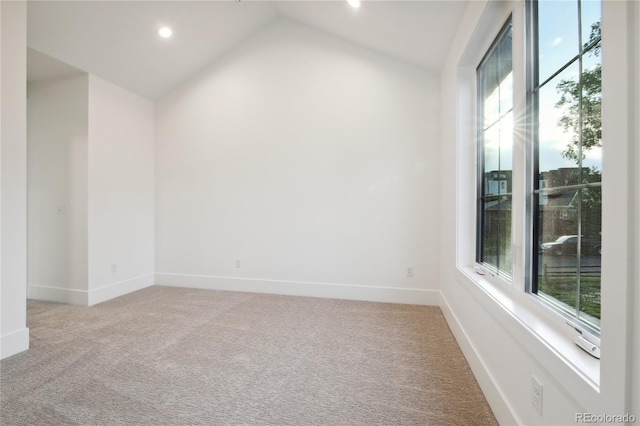 carpeted spare room with vaulted ceiling