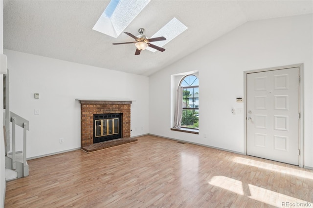 1826 Palm Dr, Colorado Springs, CO 80918 - unfurnished living room featuring a skylight, light wood-style floors, ceiling fan, a brick fireplace, and high vaulted ceiling