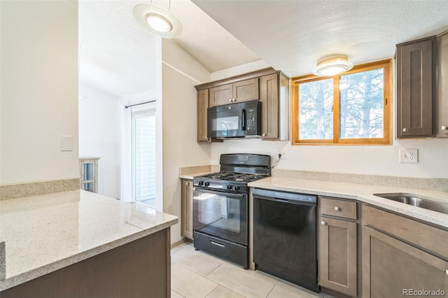 1826 Palm Dr, Colorado Springs, CO 80918 - kitchen featuring black appliances, light tile patterned floors, a textured ceiling, plenty of natural light, and light stone countertops