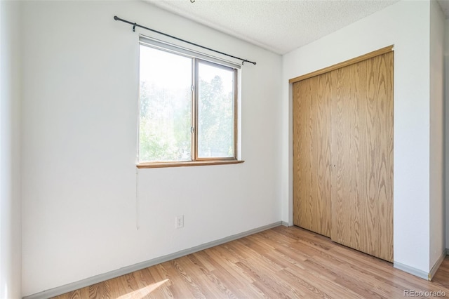 1826 Palm Dr, Colorado Springs, CO 80918 - unfurnished bedroom featuring multiple windows, light wood finished floors, a closet, and a textured ceiling