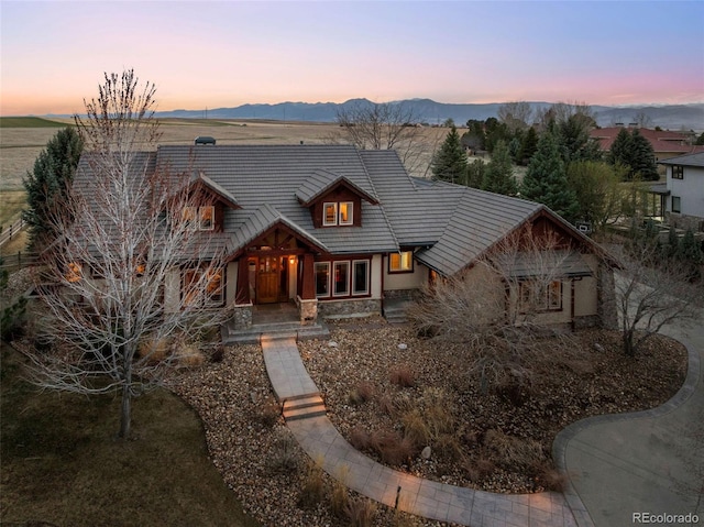 chalet / cabin with a mountain view, a tiled roof, a porch, and stone siding