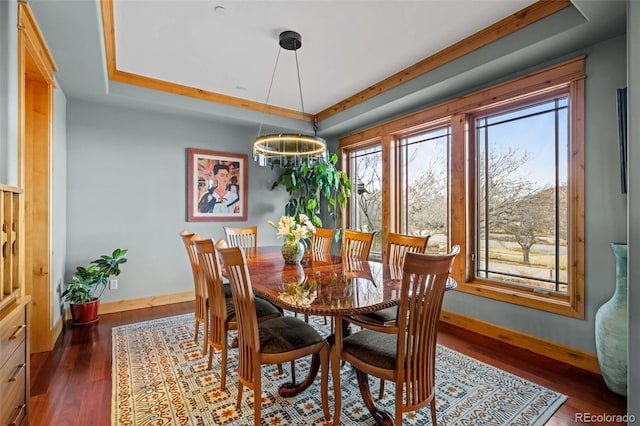 dining area with baseboards, a tray ceiling, dark wood-style flooring, and a notable chandelier