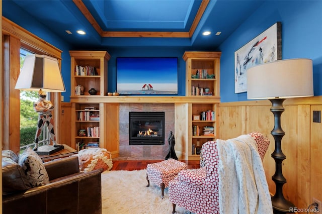 living area featuring built in features, plenty of natural light, wood finished floors, and a fireplace