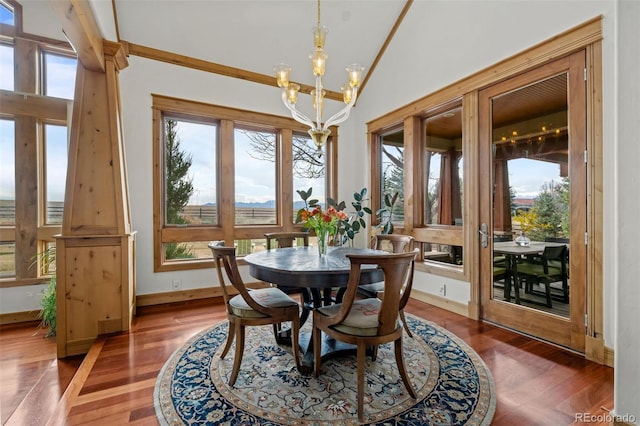 dining area with baseboards, wood finished floors, a notable chandelier, and vaulted ceiling