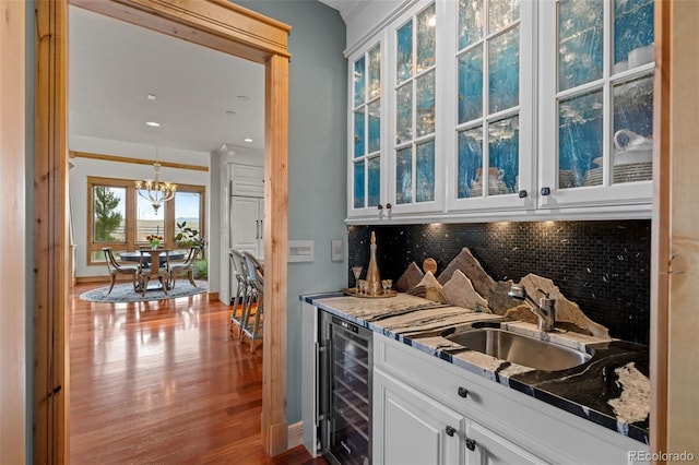 bar with decorative backsplash, wet bar, wood finished floors, a sink, and wine cooler