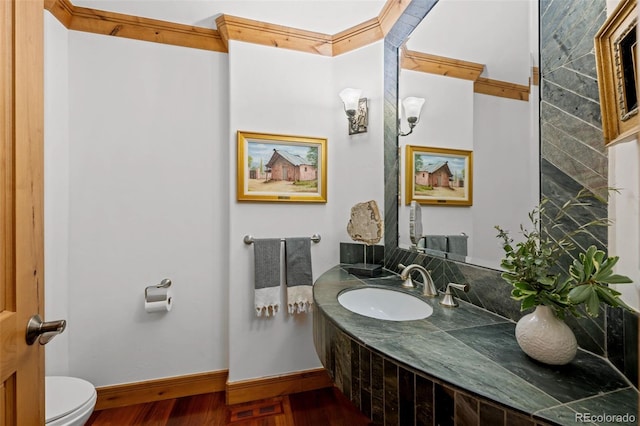 bathroom featuring toilet, baseboards, wood finished floors, and vanity