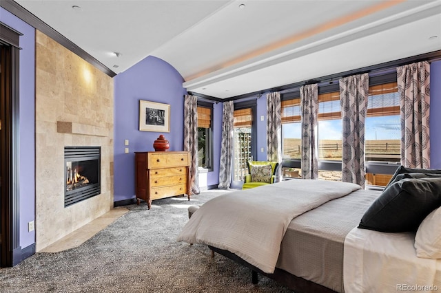 bedroom featuring lofted ceiling and a tile fireplace
