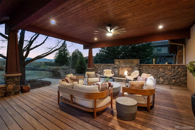 deck at dusk with an outdoor living space with a fireplace