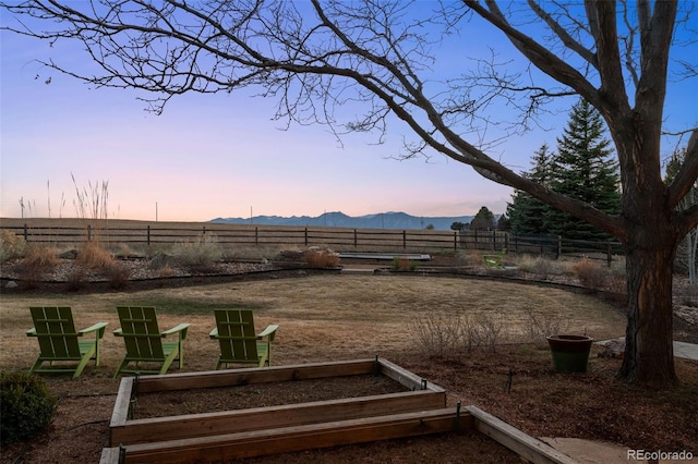 yard at dusk featuring fence and a mountain view
