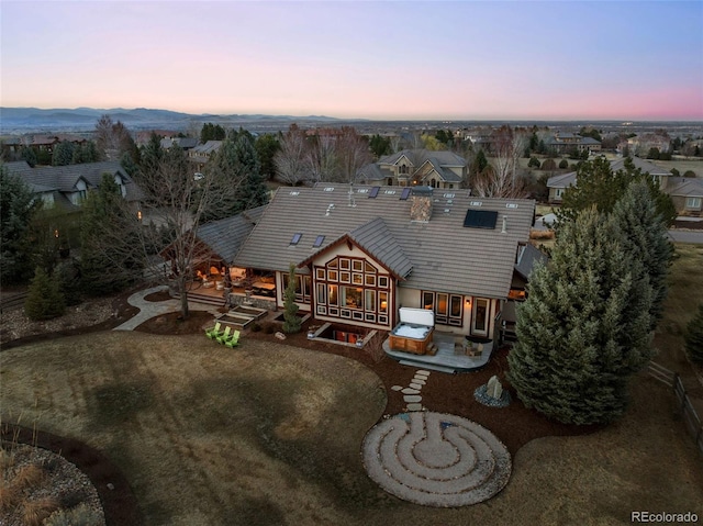 back of house at dusk with a patio and a tiled roof