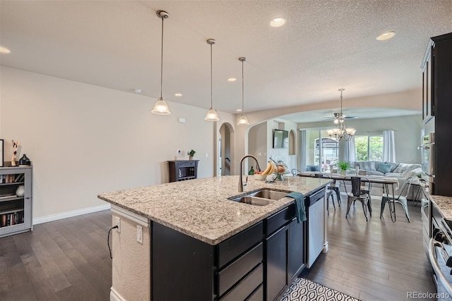 kitchen with appliances with stainless steel finishes, dark hardwood / wood-style floors, a center island with sink, and decorative light fixtures