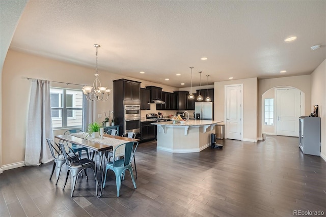 dining space with an inviting chandelier, a textured ceiling, dark hardwood / wood-style flooring, and a healthy amount of sunlight