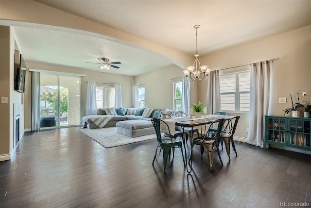 dining area featuring a textured ceiling, dark hardwood / wood-style flooring, a wealth of natural light, and ceiling fan with notable chandelier