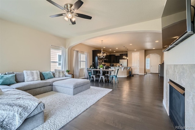 living room with ceiling fan with notable chandelier and dark hardwood / wood-style flooring