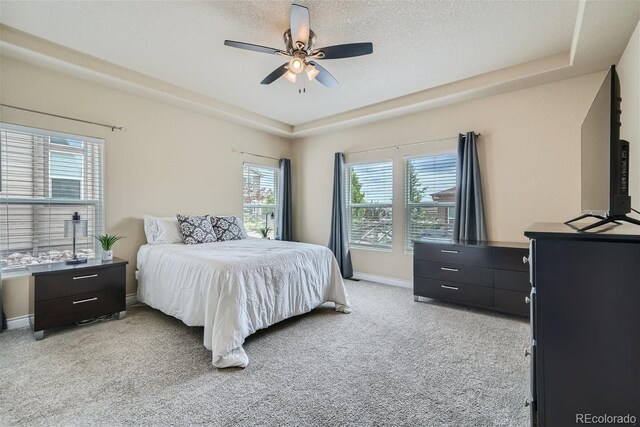 carpeted bedroom featuring ceiling fan and a tray ceiling