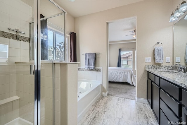 bathroom featuring plus walk in shower, vanity, hardwood / wood-style flooring, and ceiling fan