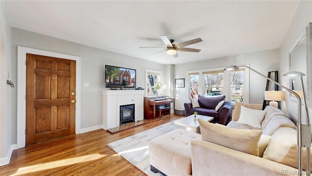 living room featuring light wood-type flooring, a ceiling fan, and baseboards