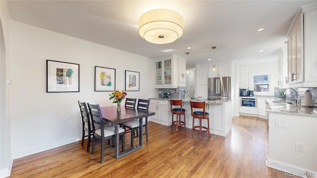 dining area featuring light wood finished floors, baseboards, and recessed lighting