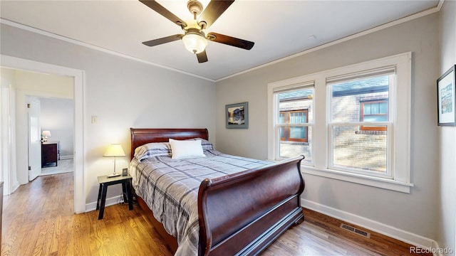 bedroom featuring baseboards, visible vents, ceiling fan, ornamental molding, and wood finished floors