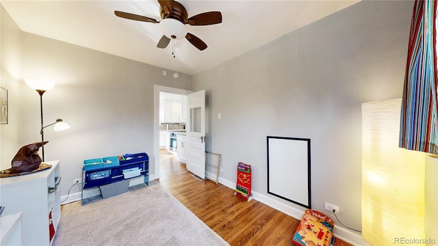 recreation room featuring a ceiling fan, light wood-style flooring, and baseboards