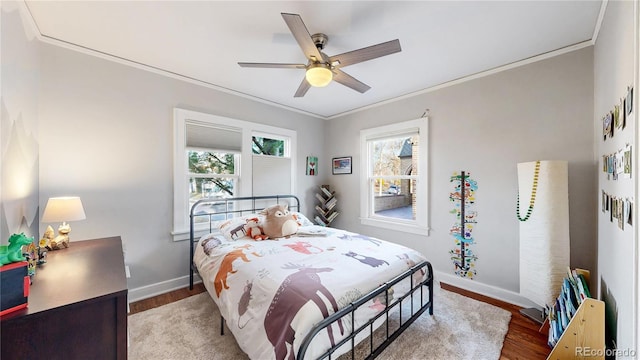 bedroom featuring baseboards, multiple windows, wood finished floors, and crown molding