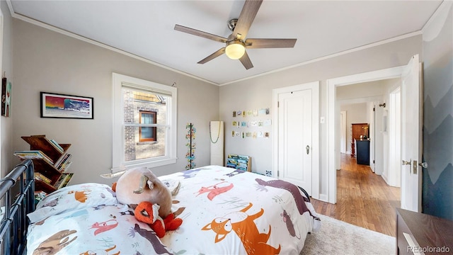 bedroom featuring ceiling fan, light wood-type flooring, and crown molding