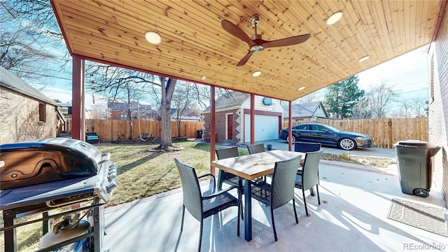 view of patio featuring an outbuilding, outdoor dining area, fence, and a ceiling fan