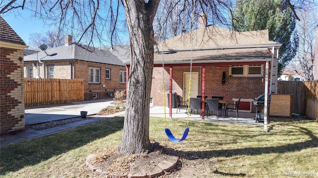 rear view of property with a patio area, brick siding, fence, and a lawn